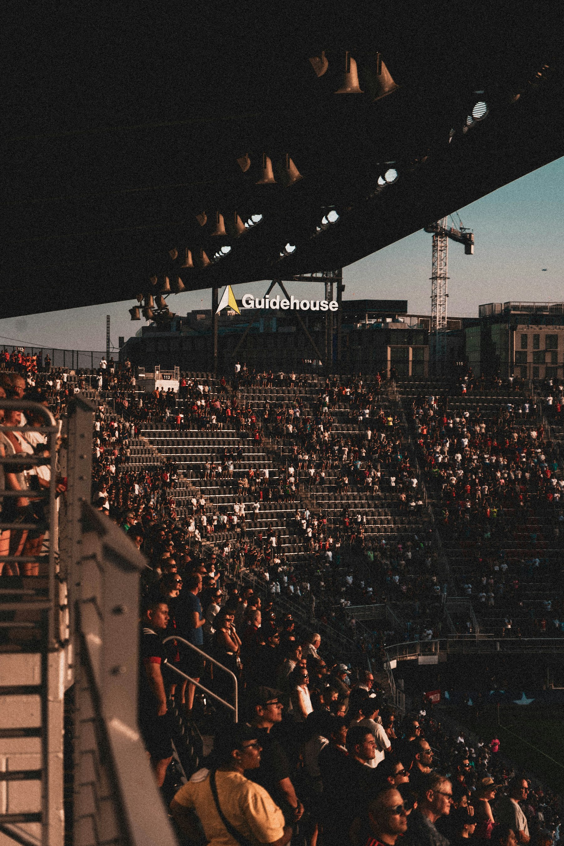 Real soccer crowd inside a stadium at sunset with supporters filling the stands